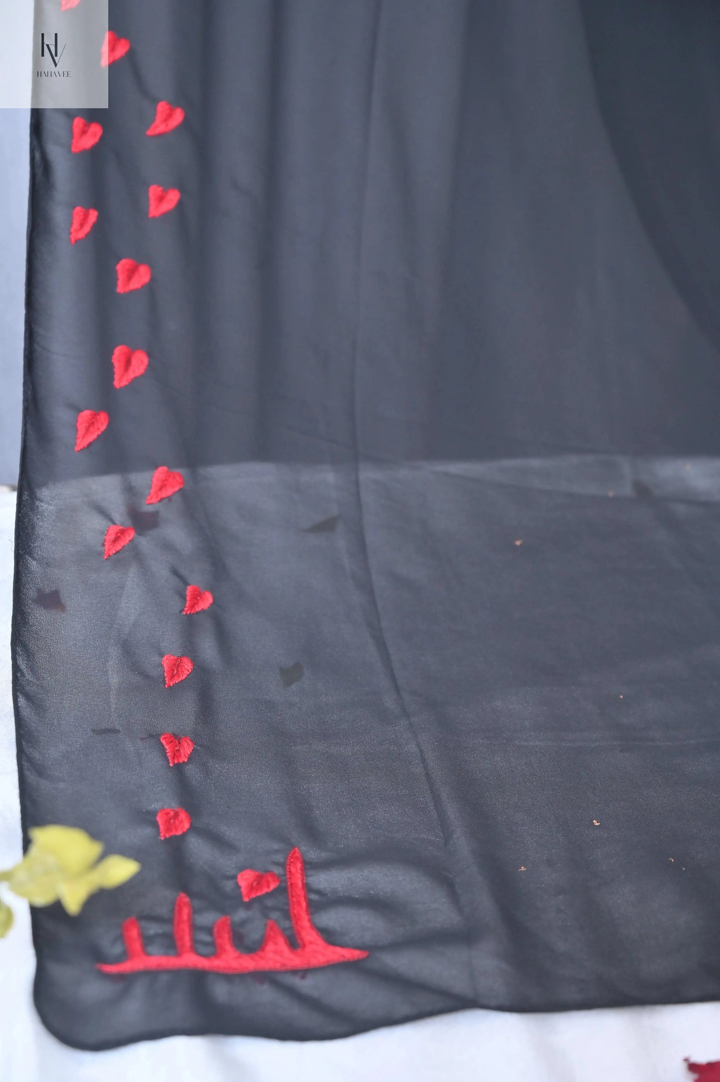Black fabric with red heart patterns and yellow flower on a white background