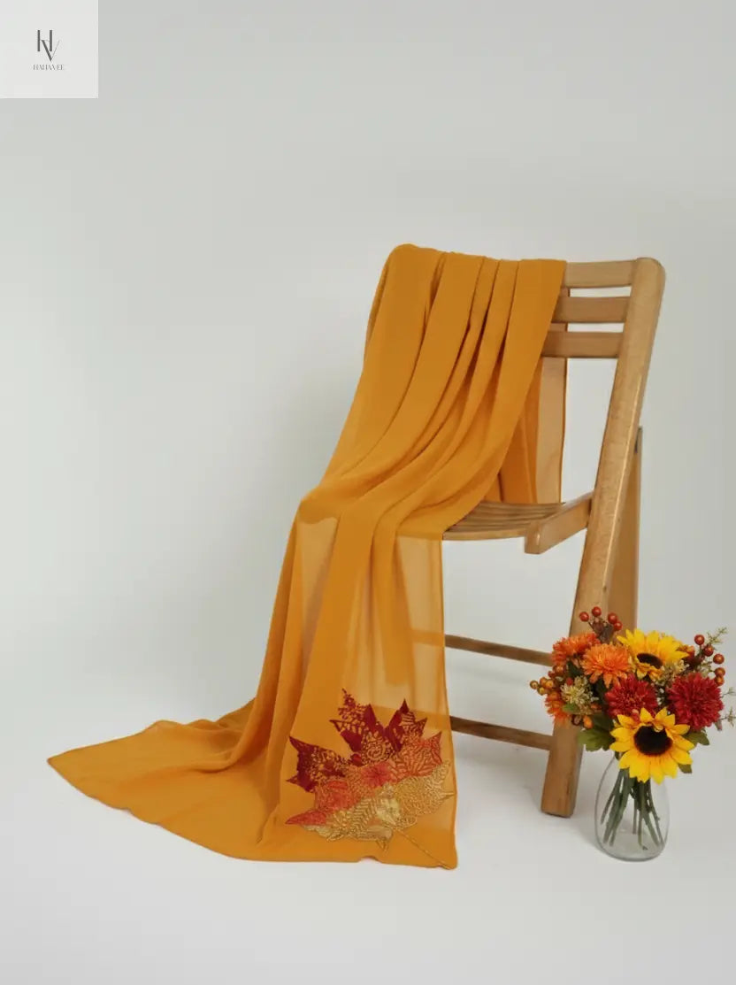 Yellow scarf draped over a wooden chair with a vase of flowers on a white background
