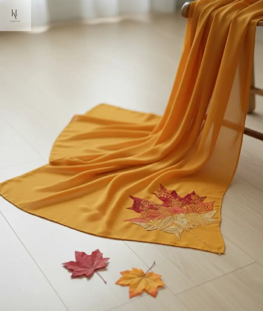 Yellow fabric with embroidered leaves on a light wooden floor