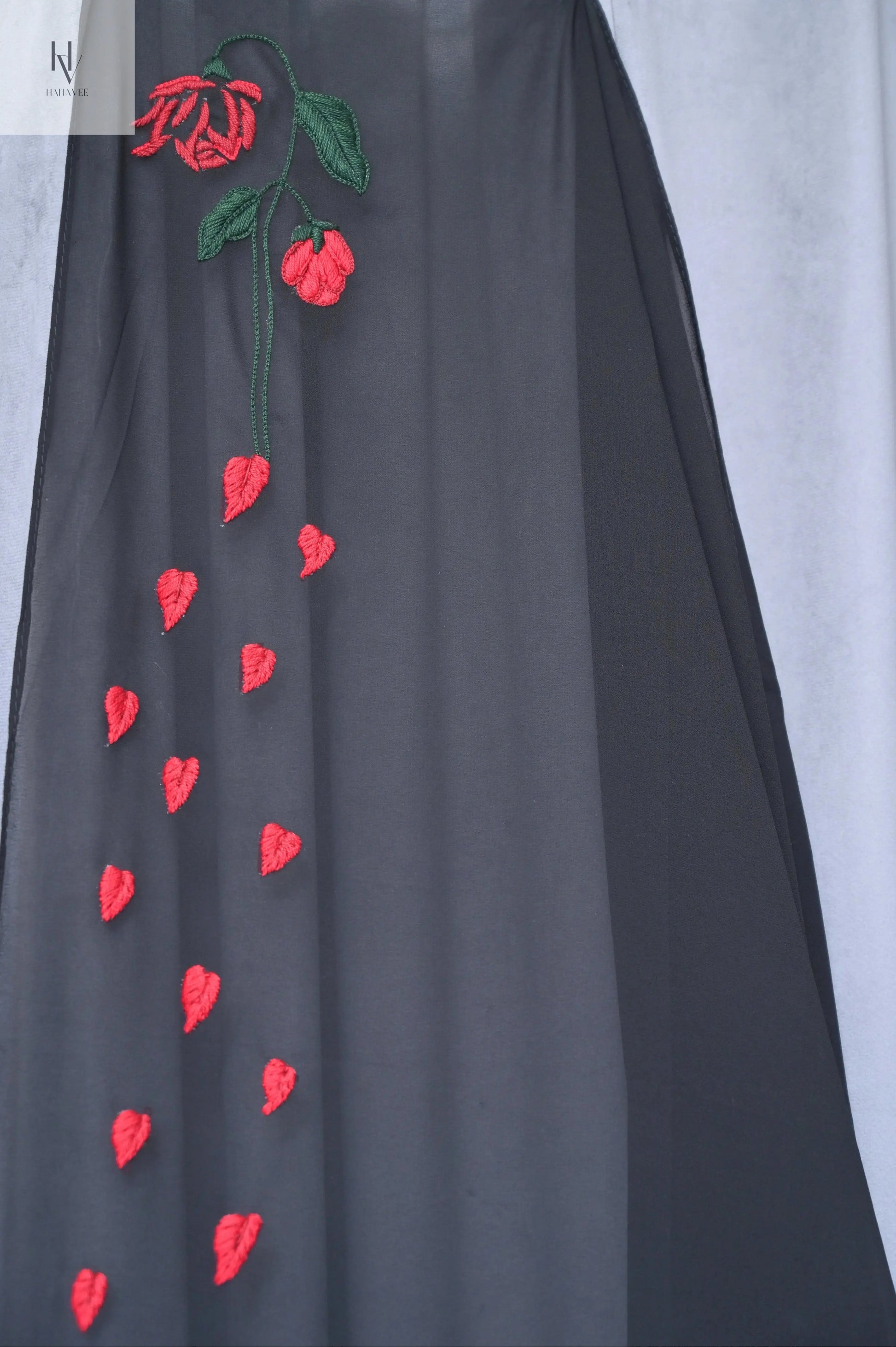 Black fabric with red floral embroidery on a white background
