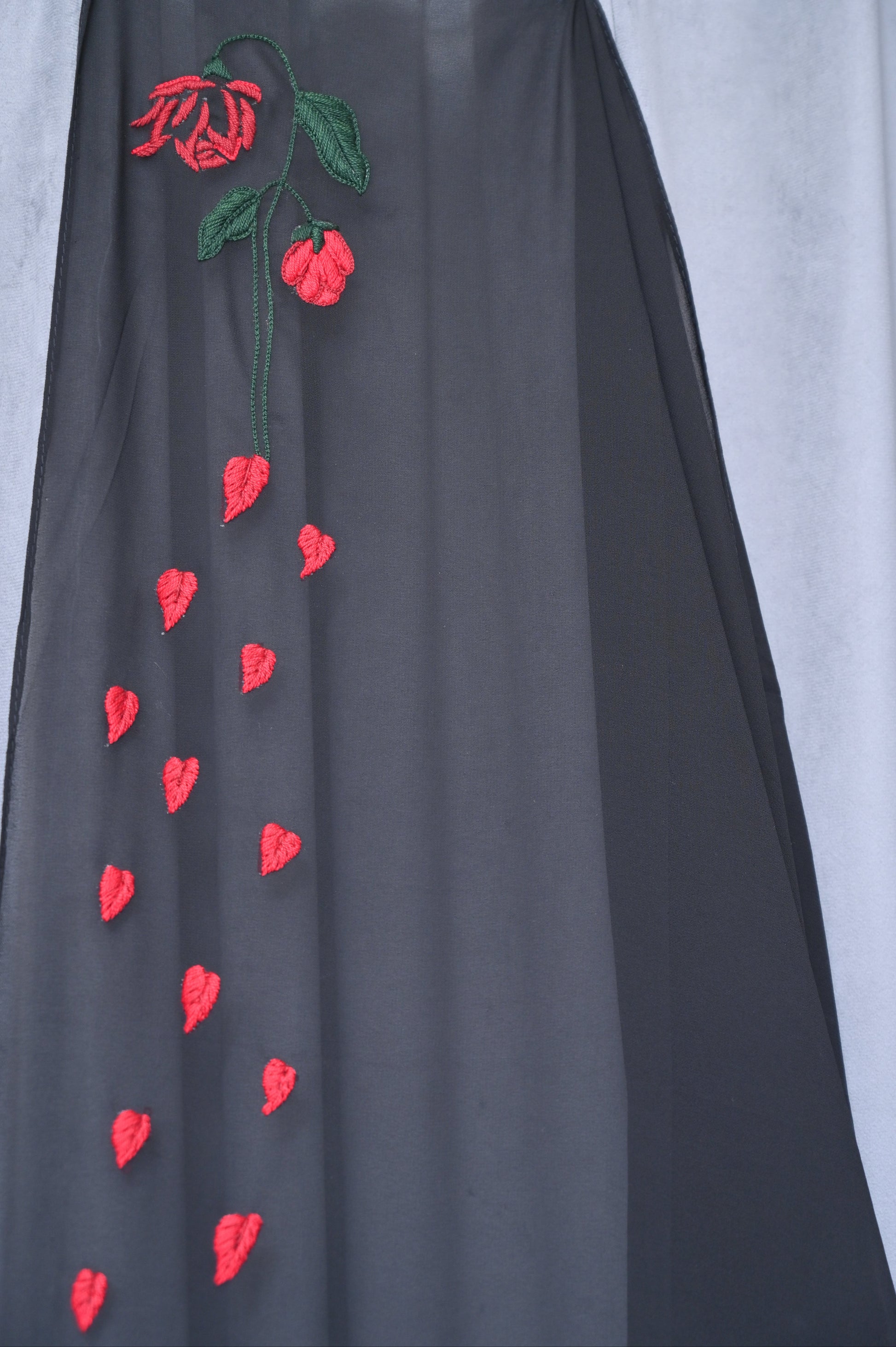 Black fabric with red floral embroidery on a white background